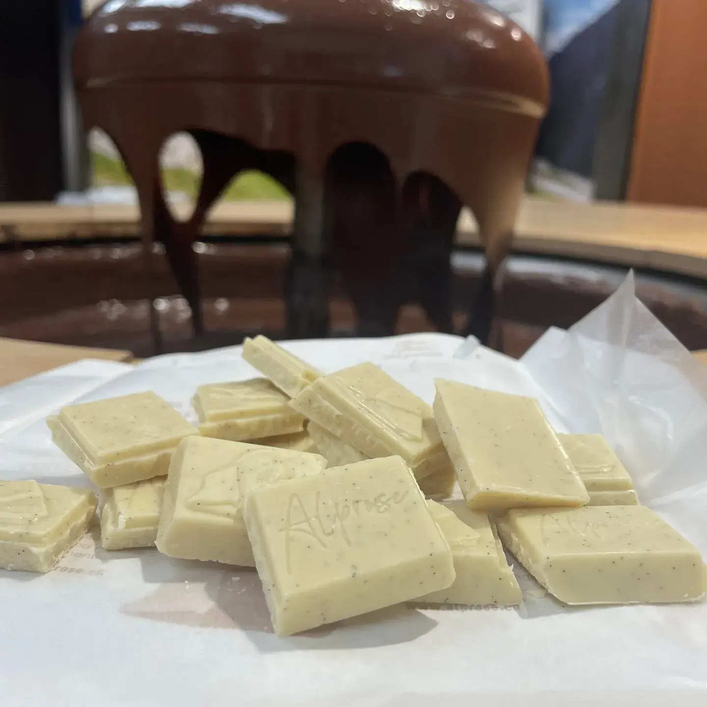 Alpirose lugano museum chocolate factory white chocolate on a table in the foreground in the background a chocolate fountain in operation
